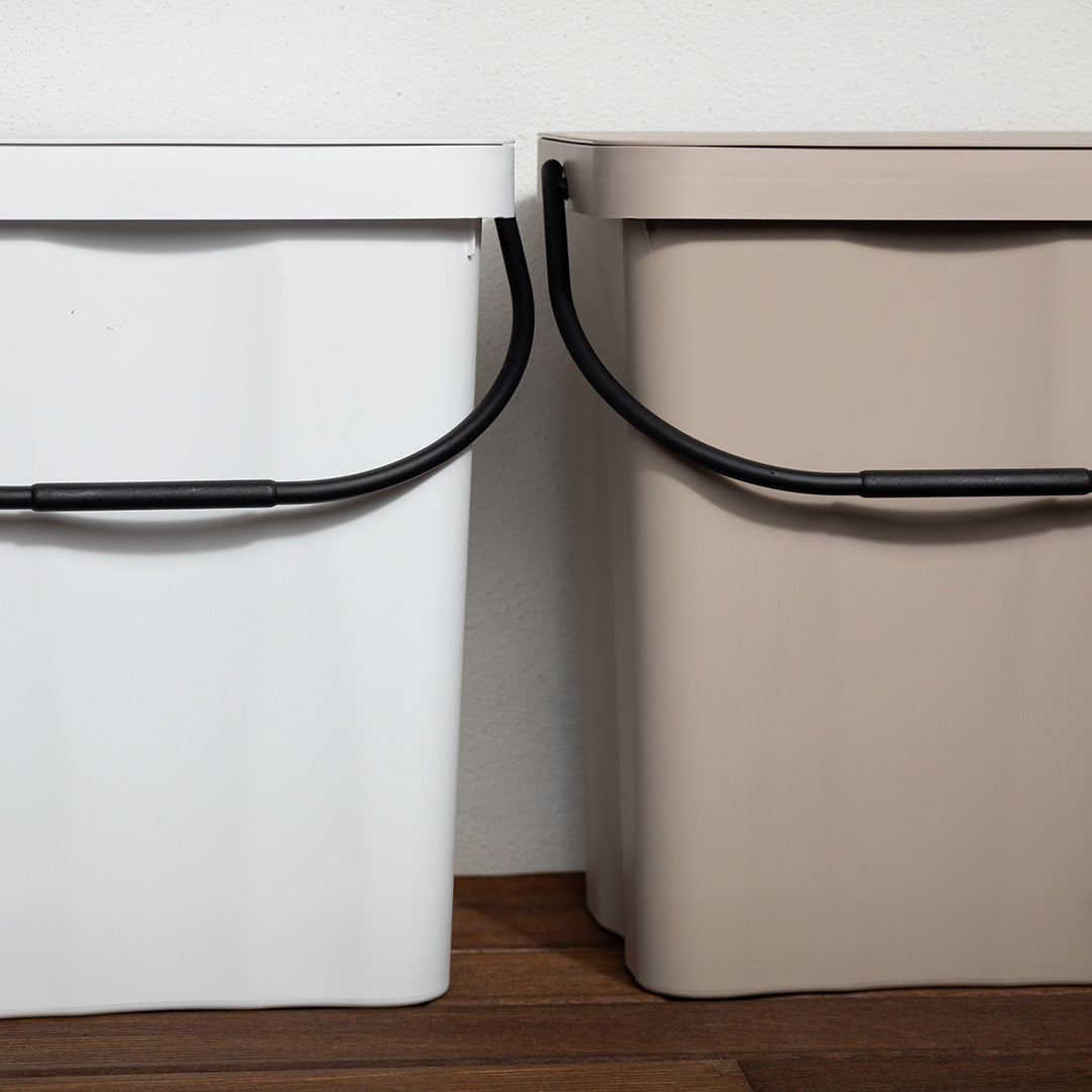 2 caixotes do lixo com asa no interior, em preto, bege e branco