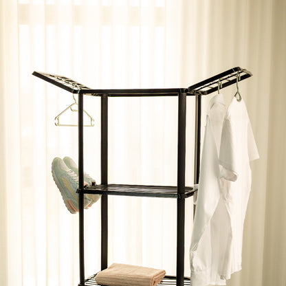Estendal verticar com 4 prateleiras de secagem de roupa, em beje, duas abas na prateleira superior, dois suportes para secagem de sapatos, com dois sapatos e dois para secagem de meias, na segunda prateleira de secagem. Duas camisas penduradas em cabides, na aba direita e uma toalha pousada na terceira prateleira de secagem